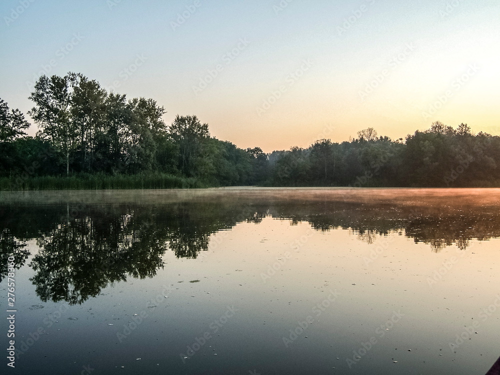Fototapeta premium Sunset over the river. Red sun. Beautiful evening background