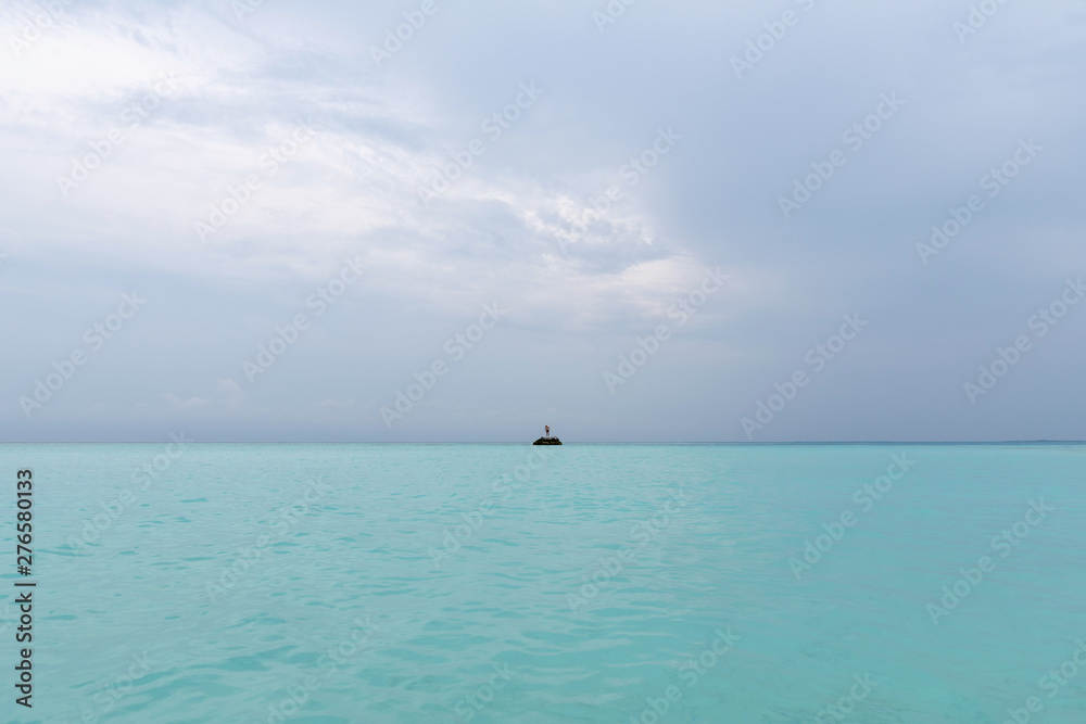 A guy is standing on a rock in the middle of the ocean. The power of the ocean