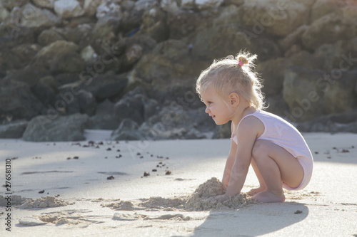 Little toddler girl playing with sand at the beach 