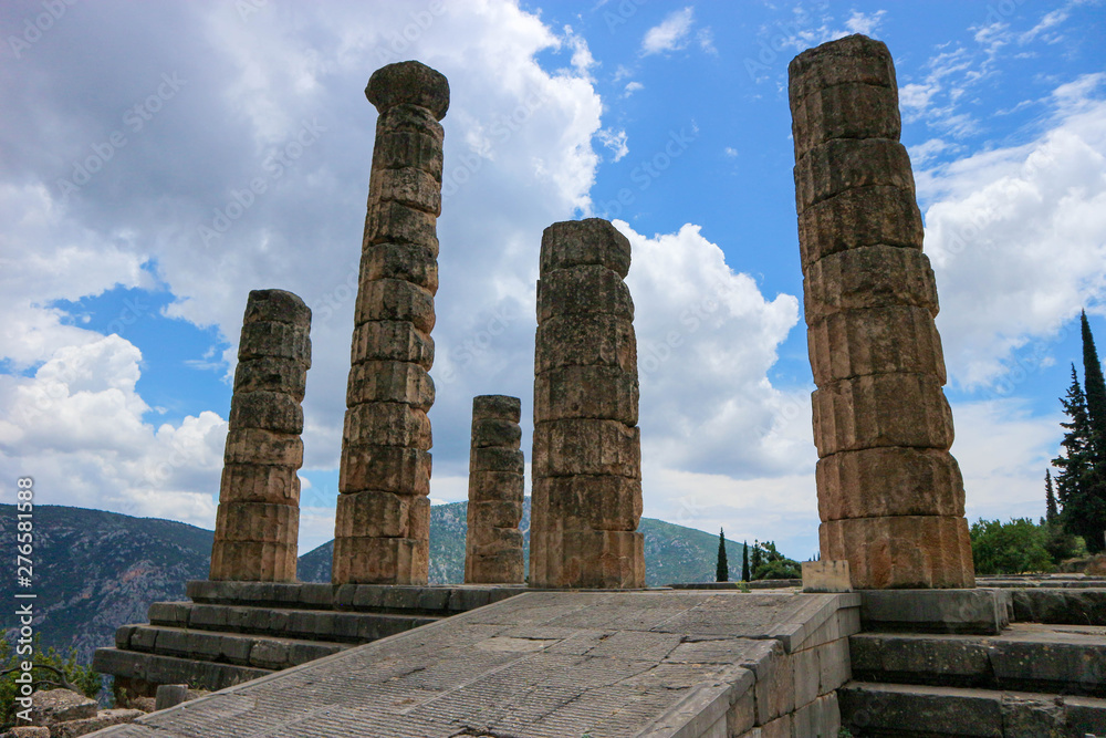 Entrance to ancient greek temple of apollo in Delphi, Greece under blue sky with clouds