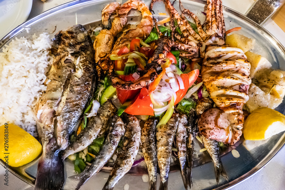 mixed grilled fish with Greek salad, rice and lemon for dinner