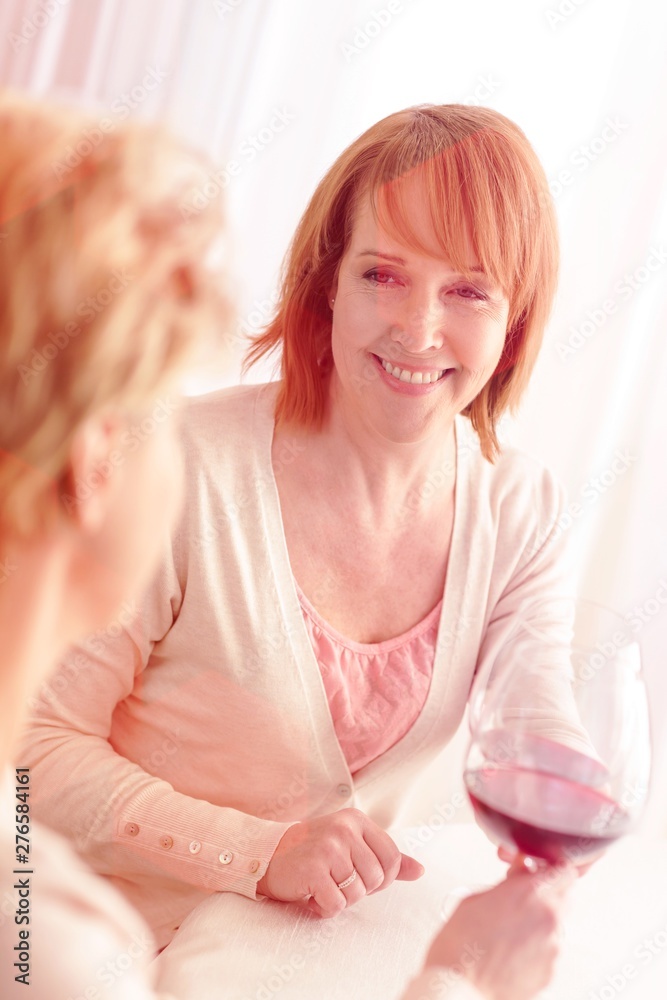Smiling women holding drinks while sitting at dining table Smiling women holding drinks while sitting at dining table