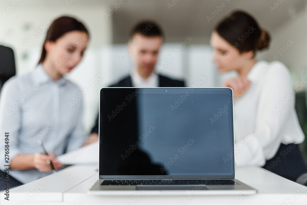blank laptop screen with copyspace in focus, office workers in a company office on a background