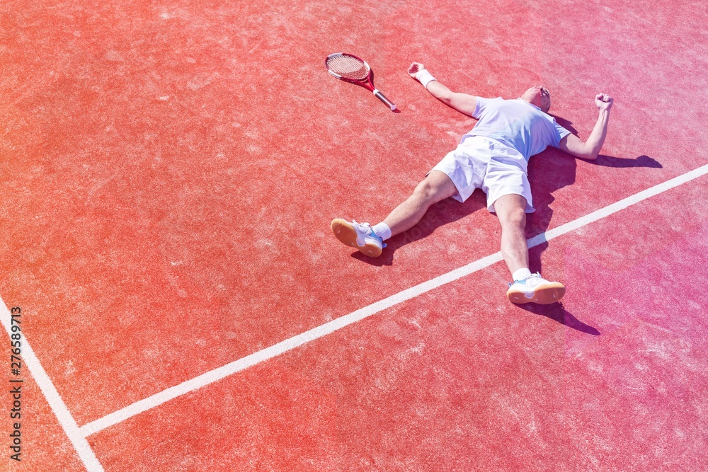 Full length of disappointed mature man lying by tennis racket on court during summer Full length of disappointed mature man lying by tennis racket on court during summer