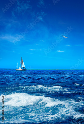Foto Seascape with sailboat on horizon over sunny blue sky
