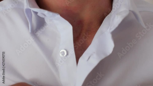 Close-up of a guy with a beard in a white shirt who stretches the buttons on the shirt. 4k. 4k video