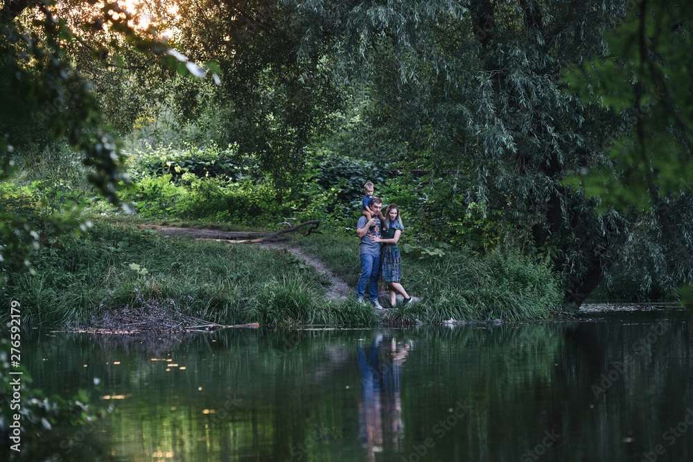 family together on the bank of the river are looking in the water family together on the bank of the river are looking in the water
