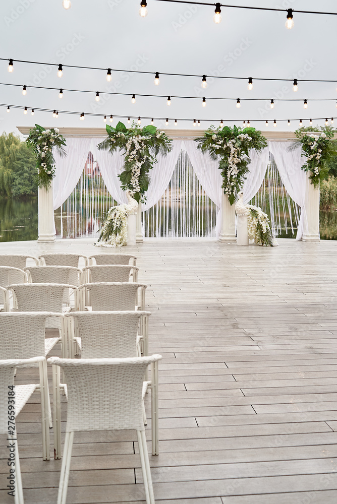 Wedding ceremony with arch, orchid flowers, chairs and bulb in forest outdoors, copy space. Wedding decorations