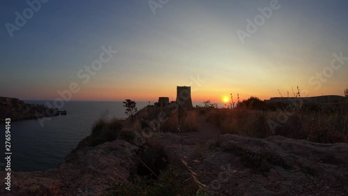 The Beautiful Ghajn Tuffieha Watch Tower At Sunset With Tourists passing by filming and taking photographs photo