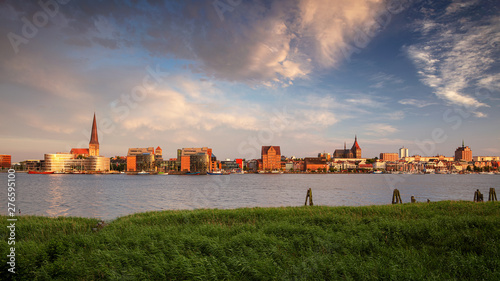 Rostock, Germany. Panoramic cityscape image of Rostock riverside with St. Peter's Church during summer sunset.