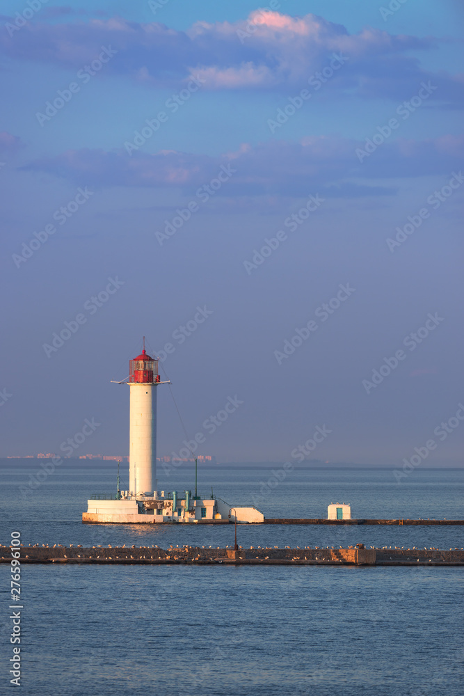 White lighthouse in seaport at evening