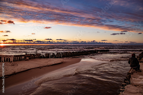 colorful sunset over the Polish Baltic sea with dark sky clouds and breakwater