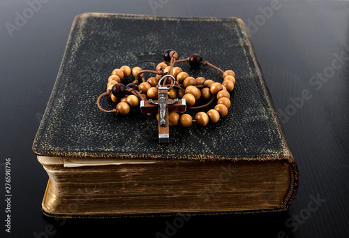 Rosary beads and prayer book on dark background. photo