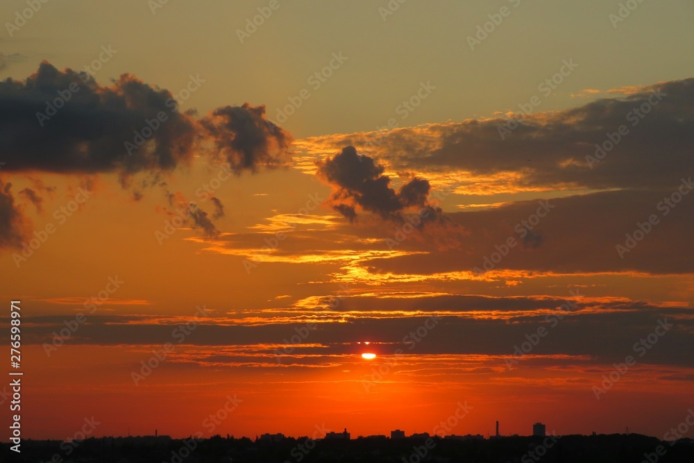 Beautiful orange sunset with dark clouds over the city, natural background