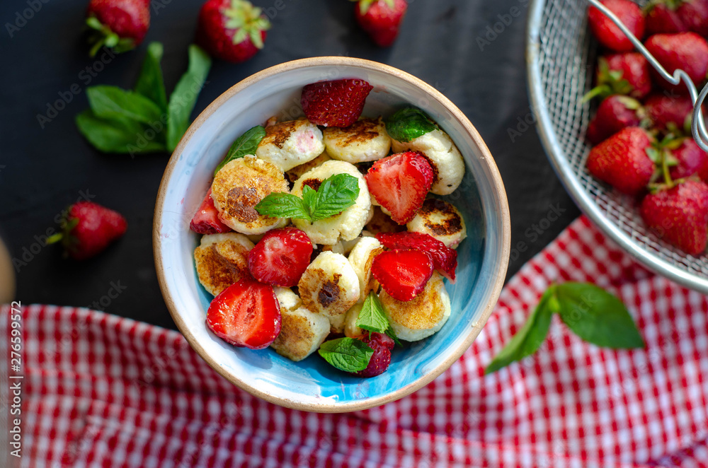 mini cheese pancakes with honey and strawberries on black background. proper nutrition healthy dessert