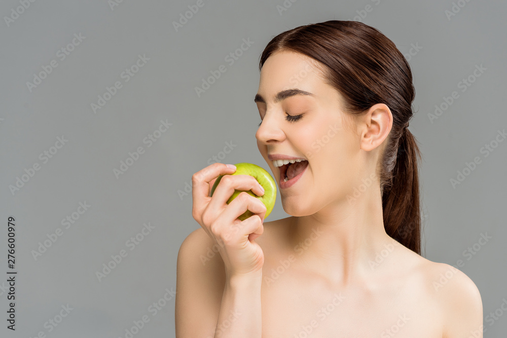 happy woman holding green apple near open mouth isolated on grey happy woman holding green apple near open mouth isolated on grey