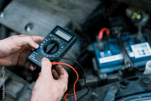 cropped view of car mechanic holding measuring device in car service