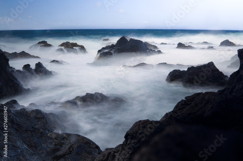 Larga exposición de rocas en el mar con efecto de humo. Misterio y niebla