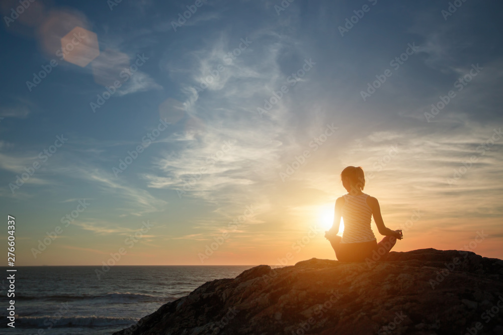 Silhouette yoga girl on the background of the sea morning meets the dawn. Healthy lifestyle.