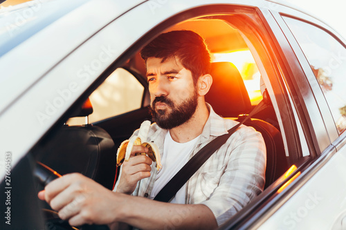 Man eating a snack while driving his car