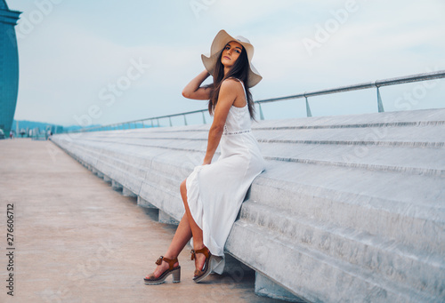 Pretty woman wearing white dress and pamela hat standing over the city beach, sea. Happy summer vacation © Igor Kardasov