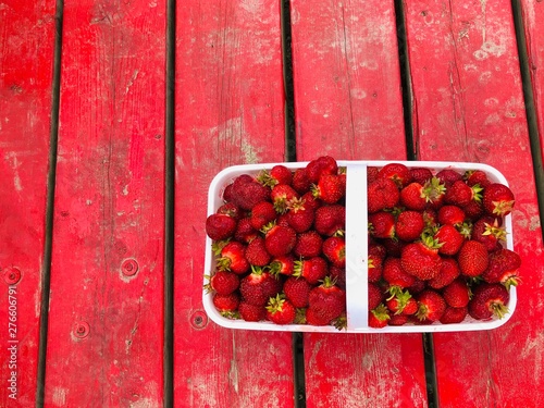 Fresh picked juicy Strawberries in a basket on a red wood background  photo