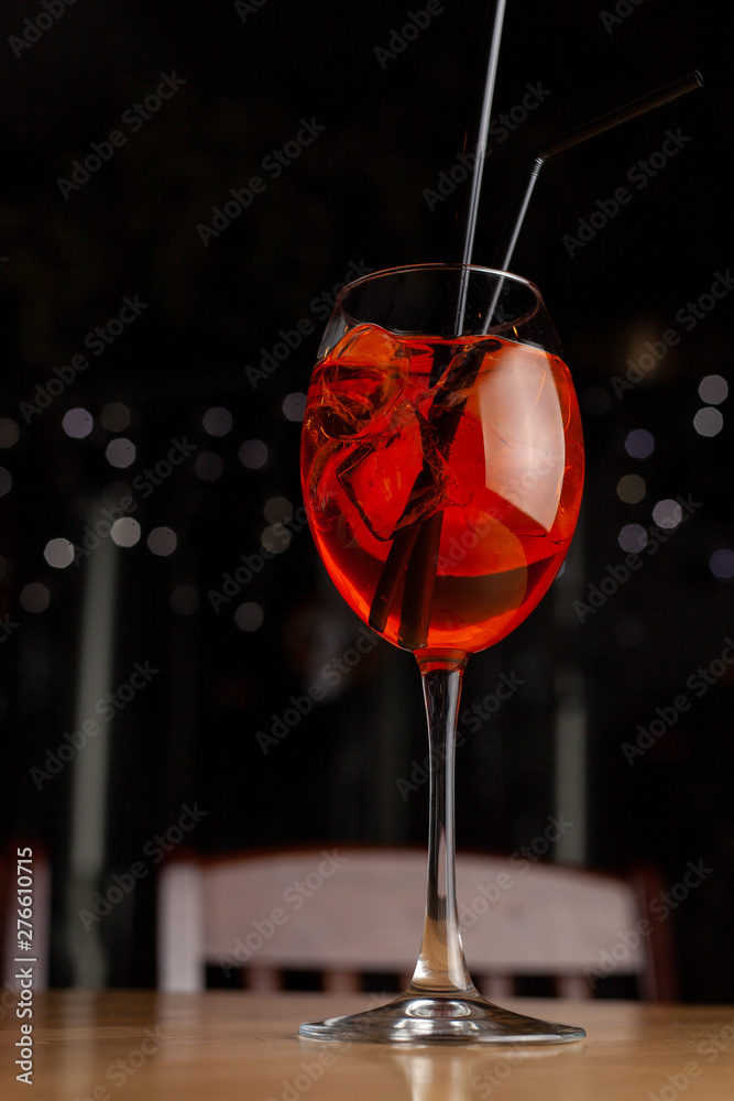 Aperol Spritz in a wine glass on black background with blurred bokeh lights