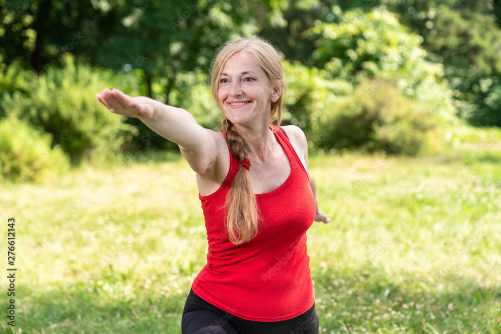 Best aged lady practice yoga doing archer pose in a park Best aged lady practice yoga doing archer pose in a park