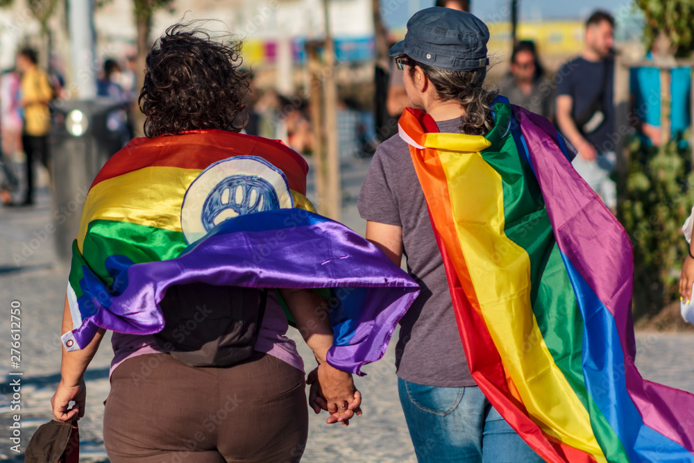 Couple of women holding hands with LGBT rainbow flags