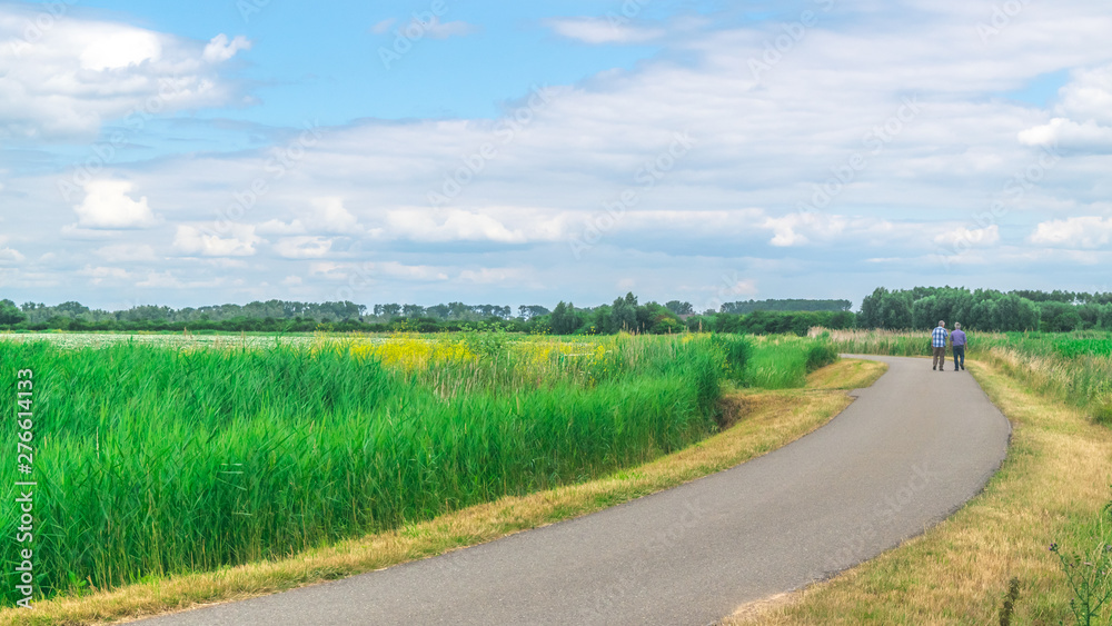Fototapeta premium Two unidentified people walking in polder