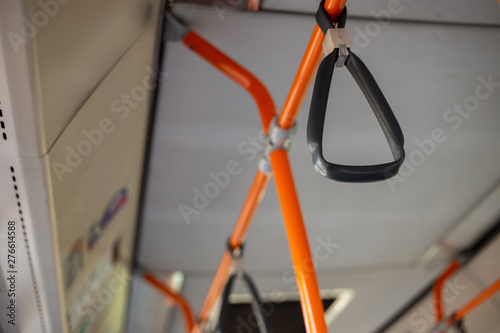 Plastic handles in bus interior hanging from orange metallic bars – Handrails and grips in a practical and comfortable mean of transport