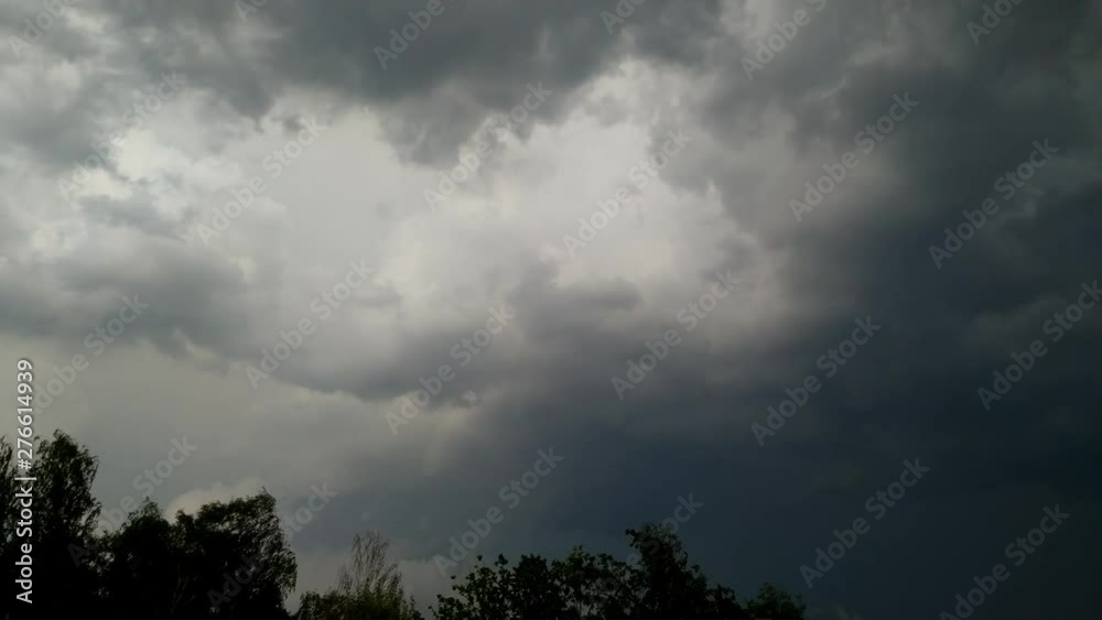 Timelapse of thunder clouds moving over the top of trees before a storm