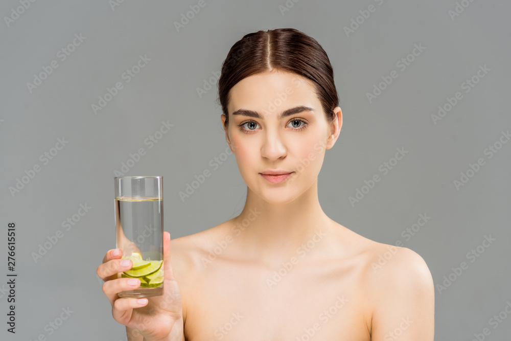 attractive young woman holding glass of water with sliced lime isolated on grey attractive young woman holding glass of water with sliced lime isolated on grey