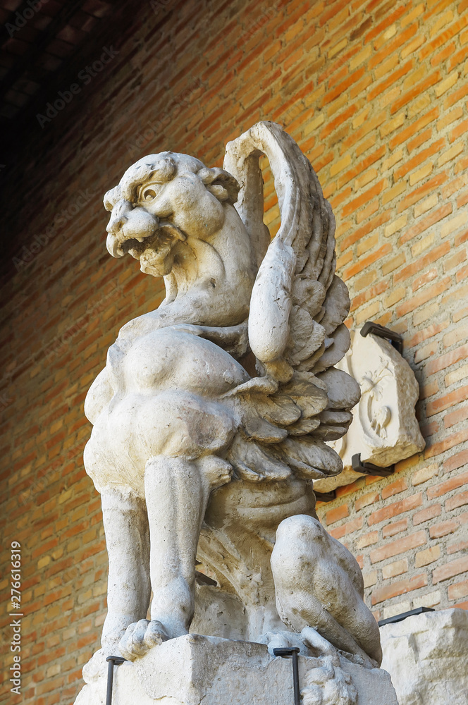 gargoyle carved in stone with a wall of bricks as background