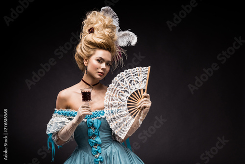Obraz na plátne attractive victorian woman holding fan and wine glass on black