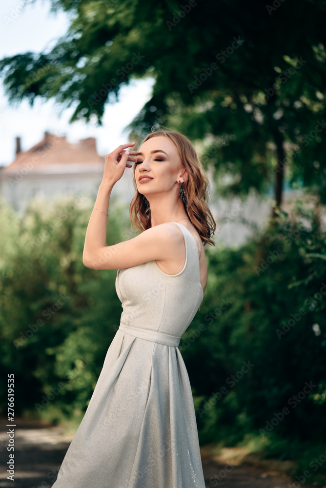 Gorgeous young model woman with perfect hair looking at camera posing in the city wearing evening dress. Gorgeous young model woman with perfect hair looking at camera posing in the city wearing evening dress.