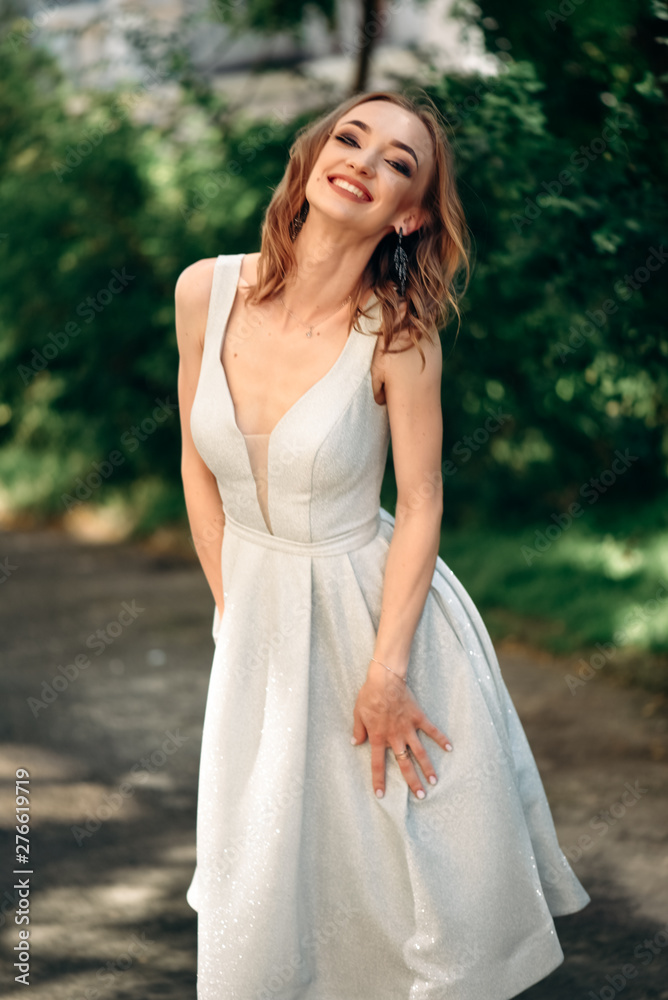 Gorgeous young model woman with perfect hair looking at camera posing in the city wearing evening dress. Gorgeous young model woman with perfect hair looking at camera posing in the city wearing evening dress.