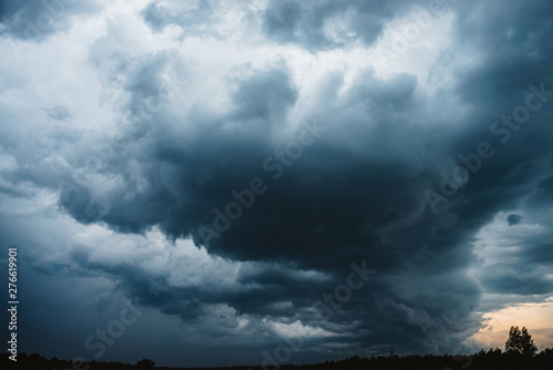 Dramatic cloudscape. Sunny light through dark heavy thunderstorm clouds before rain. Overcast rainy bad weather. Storm warning. Natural blue background of cumulonimbus. Sunlight in stormy cloudy sky. photo
