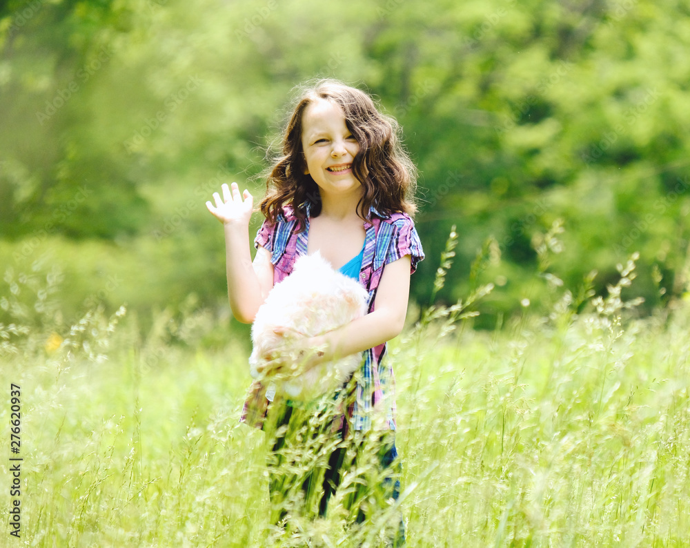 Young girl waving to camera, happy in summer grass. Young girl waving to camera, happy in summer grass.