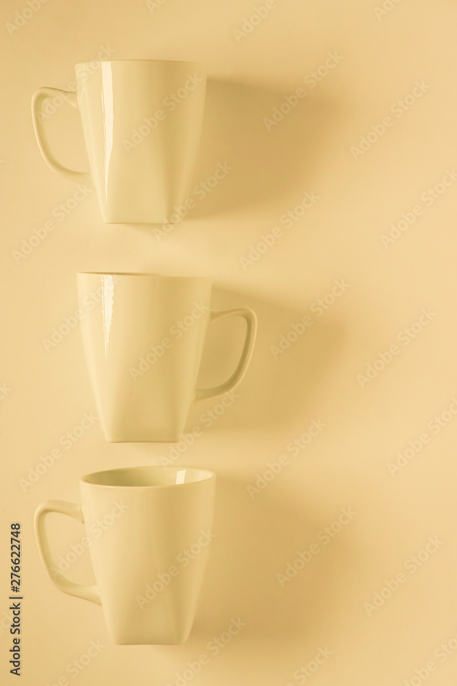3 yellow coffee mugs on yellowish background in a vertical row, empty copy space 3 yellow coffee mugs on yellowish background in a vertical row, empty copy space