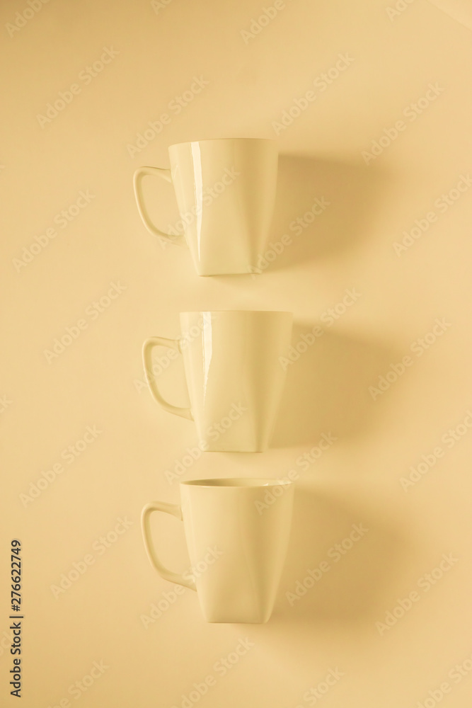 3 yellow coffee mugs on yellowish background in a vertical row, empty copy space 3 yellow coffee mugs on yellowish background in a vertical row, empty copy space