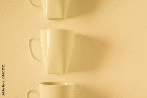 Yellow coffee mugs on yellow background in a vertical row with empty copy space