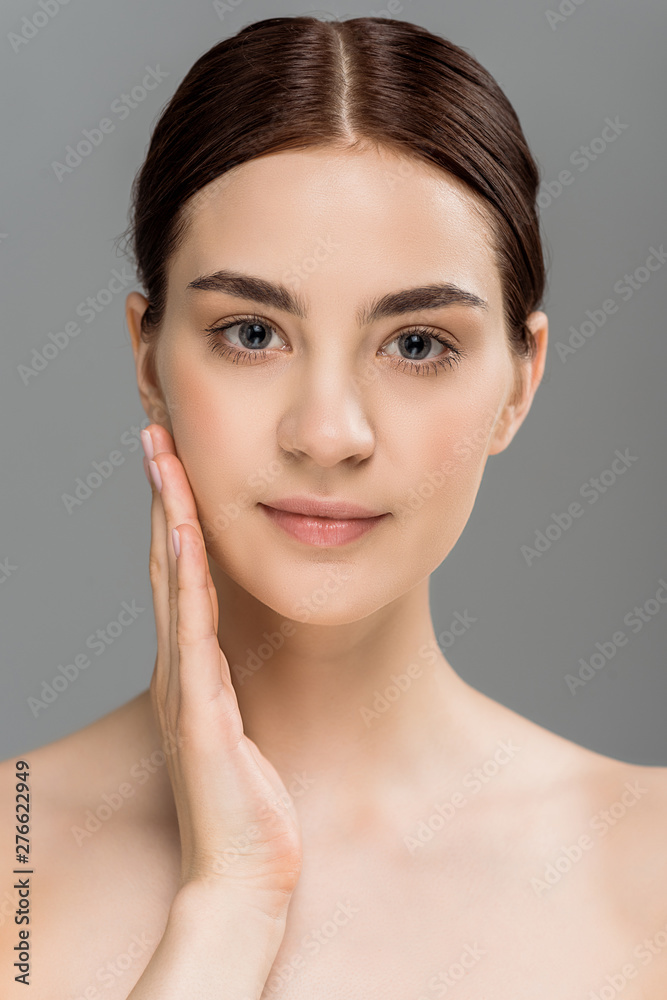 attractive young naked woman looking at camera and touching face isolated on grey attractive young naked woman looking at camera and touching face isolated on grey