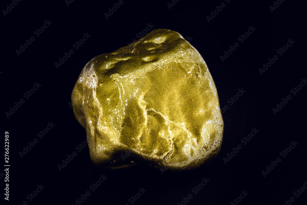 Gold nugget, large gold stone closeup isolated on black background. Concept of finance, luxury or wealth.