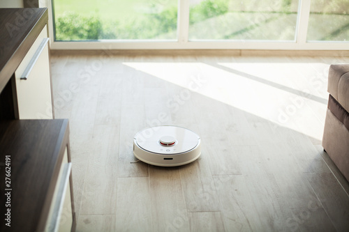 Smart House. Vacuum cleaner robot runs on wood floor in a living room