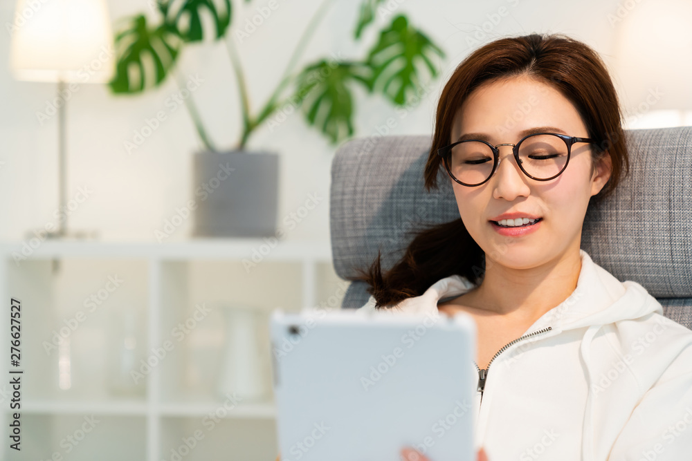 部屋でタブレットを見る女性 部屋でタブレットを見る女性