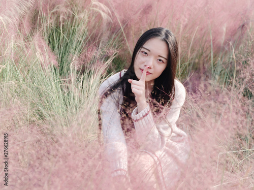 Portrait of beautiful Chinese girl put her finger on her mouth and making silent gesture in hairawn muhly field. photo