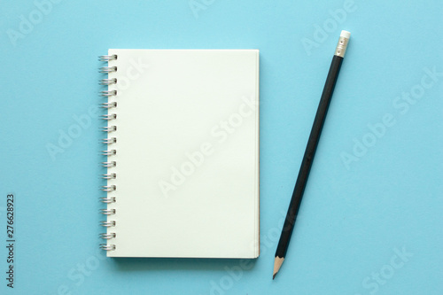 notebook and pencil on blue background