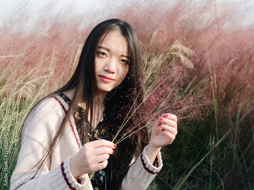 Portrait of beautiful Chinese girl holding Pink hairawn muhly in hairawn muhly field. photo