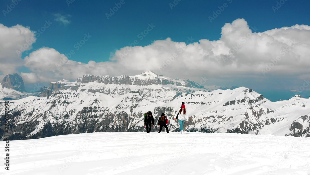 Traveling people walking upwards on the snow in Dolomites with big backpacks Traveling people walking upwards on the snow in Dolomites with big backpacks